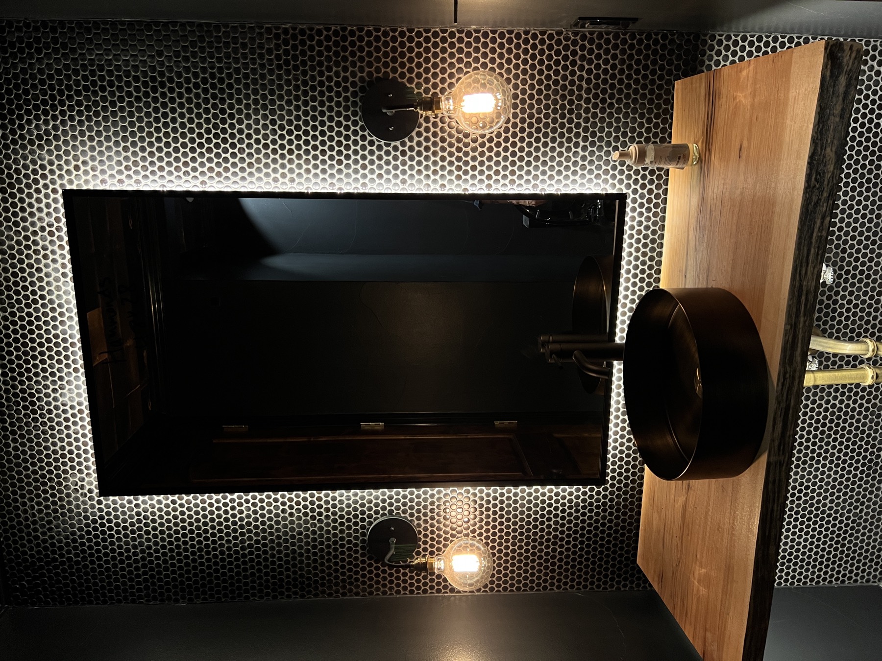 Moody powder room with halo backlit mirror over penny tile